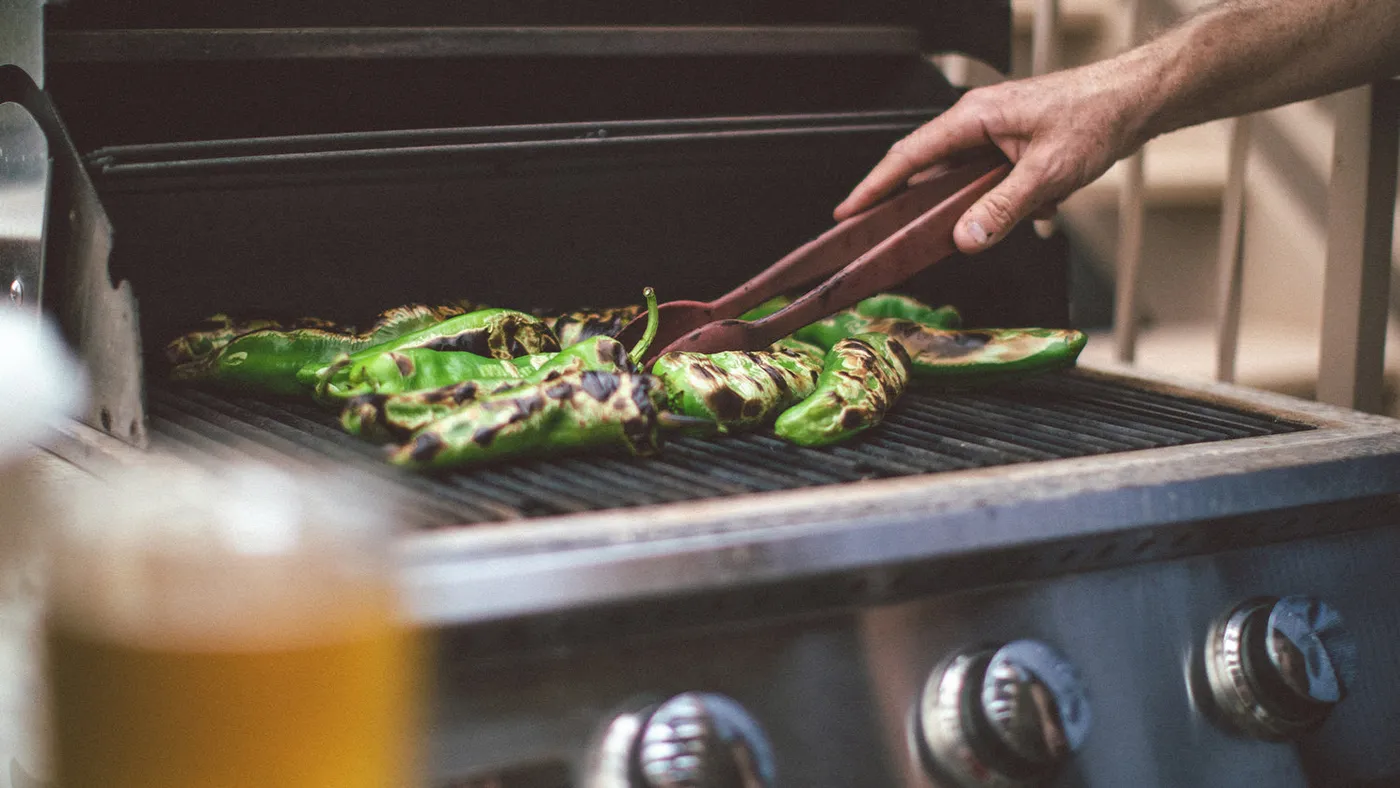 Hatch green chile peppers roasting on a grill